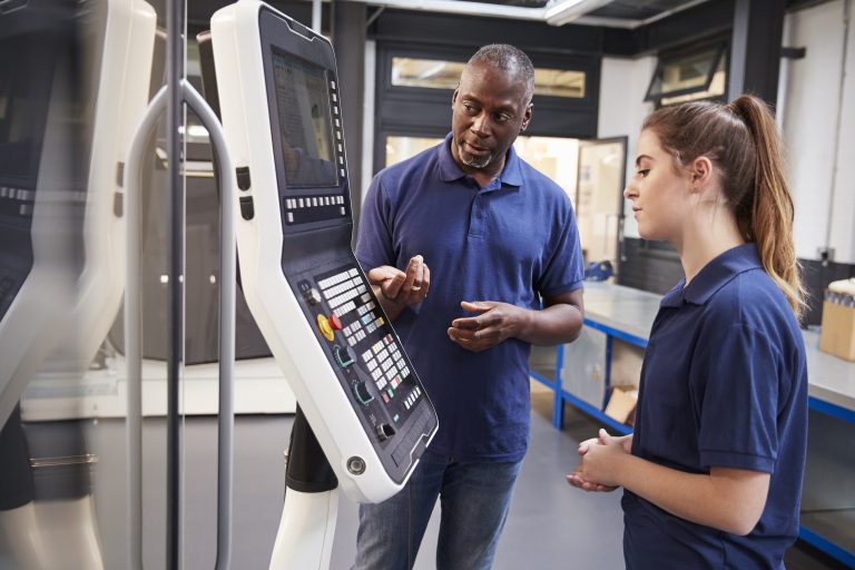 Two workers reviewing a CNC machine control panel