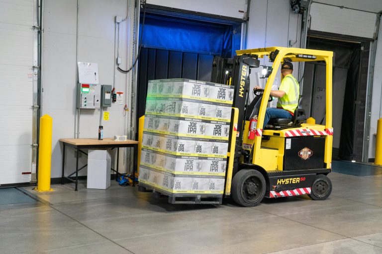 Forklift operator moving a pallet of boxed products